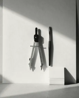 A drafting compass, a fine brush and a stack of blank paper cards.