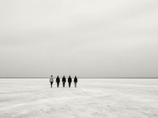 Five people walking side by side across an empty salt flat.