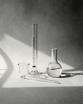A graduated cylinder, a round flask and a pipette in hard window light.